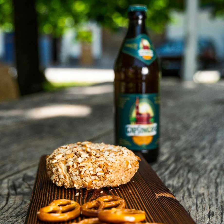 Kaese mit einer Brezenrinde und Giesinger Bier im Hintergrund
