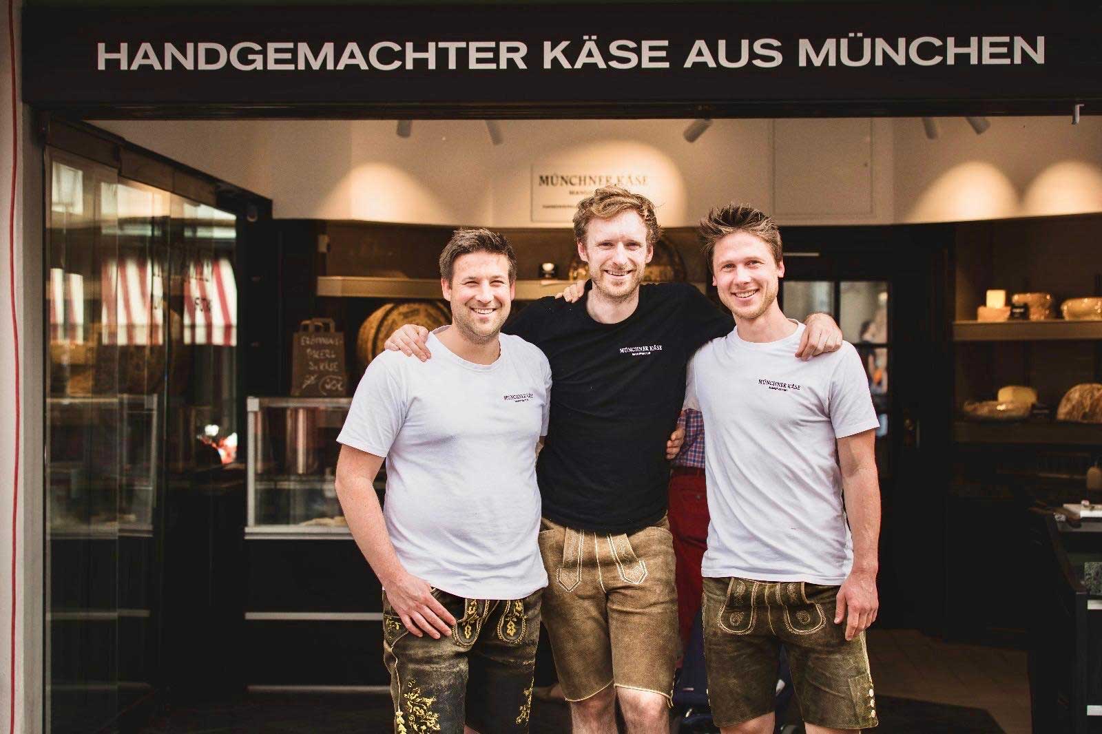 Die drei Gründer der Münchner Käse Manufaktur vor dem Stand am Viktualienmarkt.