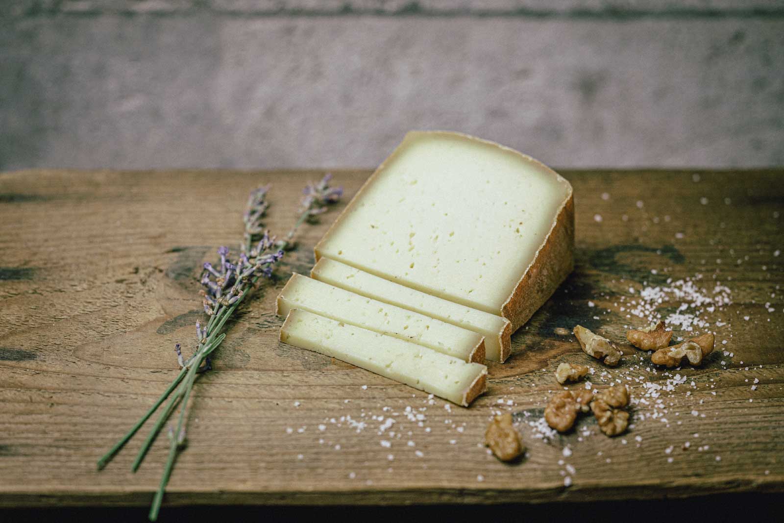 Ein Stück Hartkäse der Münchner Käse Manufaktur auf einem Holzbrett