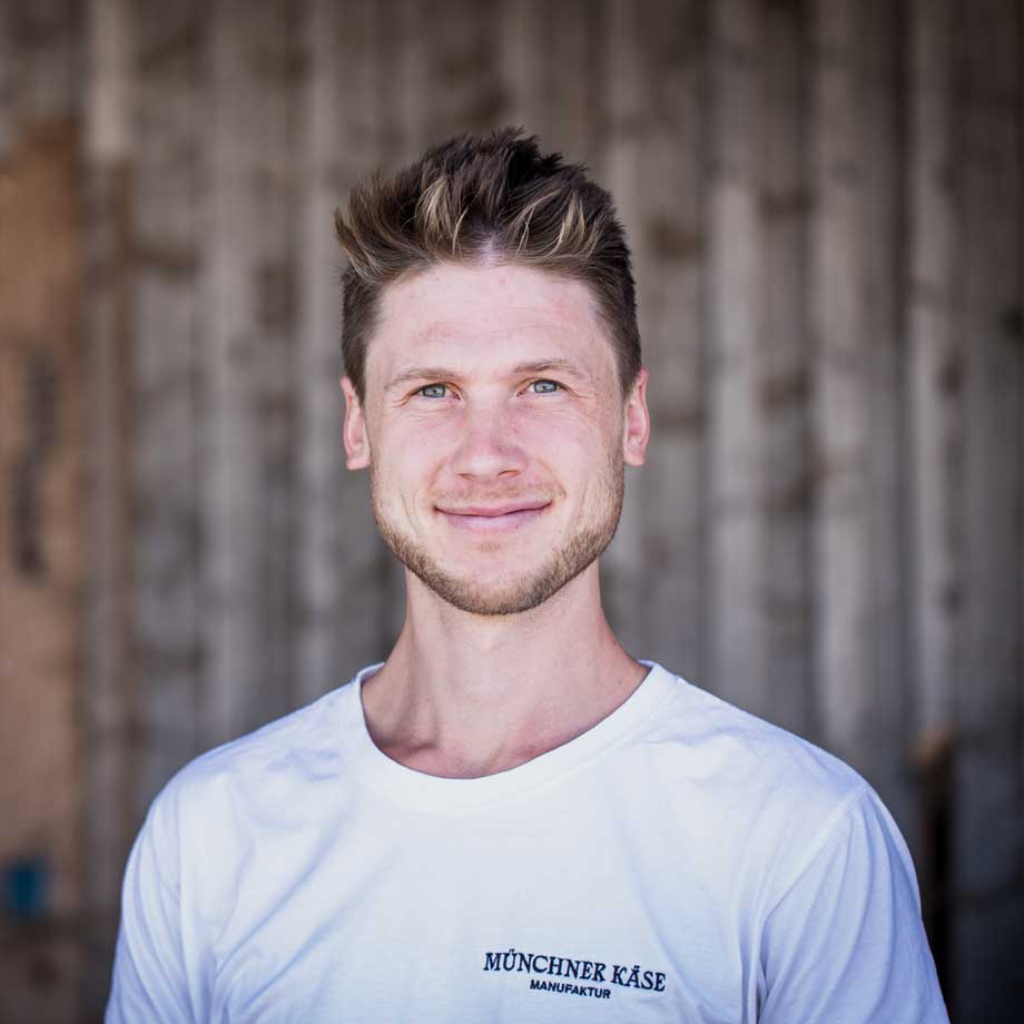 Ein Portrait von Sebastian, Gründer der Münchner Käse Manufaktur. Er lächelt.