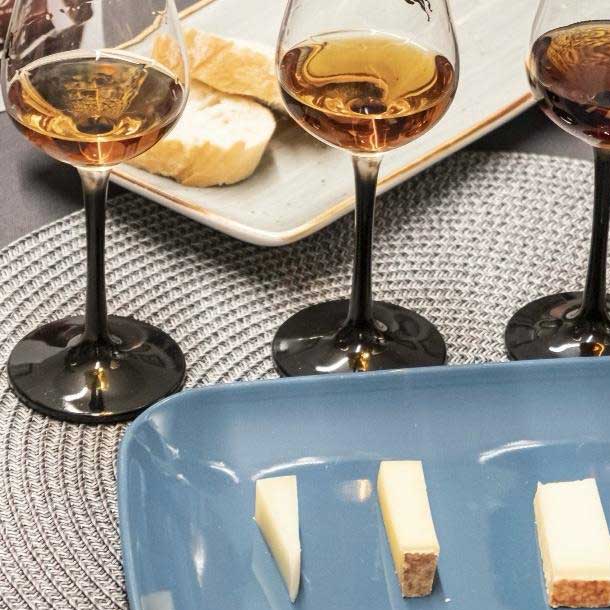 Whiskey in kleinen Nosing-Glaesern und Kaese auf einer Platte
