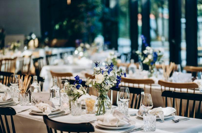 Ein feierlich gedeckter Tisch mit Servietten, Blumen und Weingläsern.