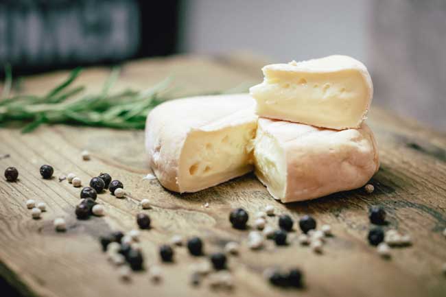 Zu sehen ist der Isarbazi, der meistverkaufte Käse der Münchner Käse Manufaktur. Er liegt auf einem Holzbrett.