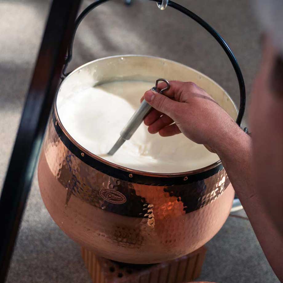 Kaesekessel voll Milch wird umgeruehrt