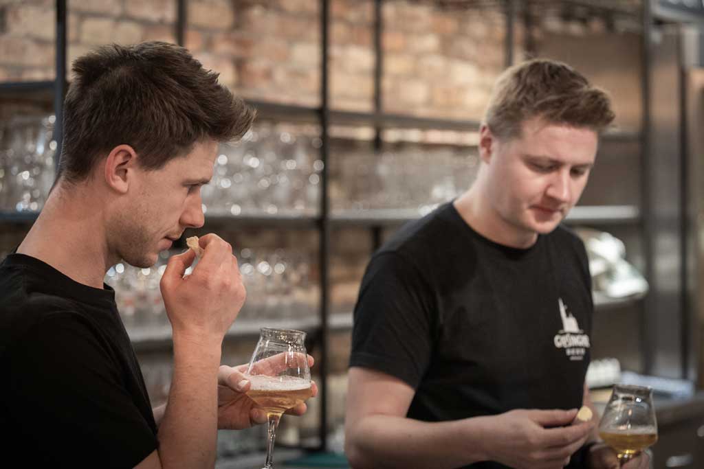 Kaesemeister und Braumeister probieren Kaese und Bier