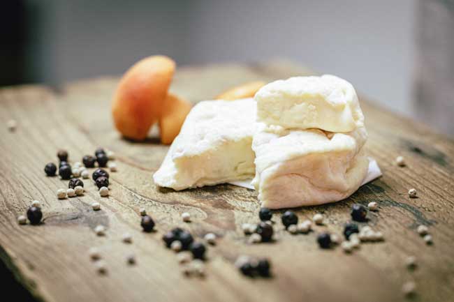 Zu sehen ist der Oida Topfen der Käse der Münchner Käse Manufaktur. Er liegt auf einem Holzbrett und ist angeschnitten.